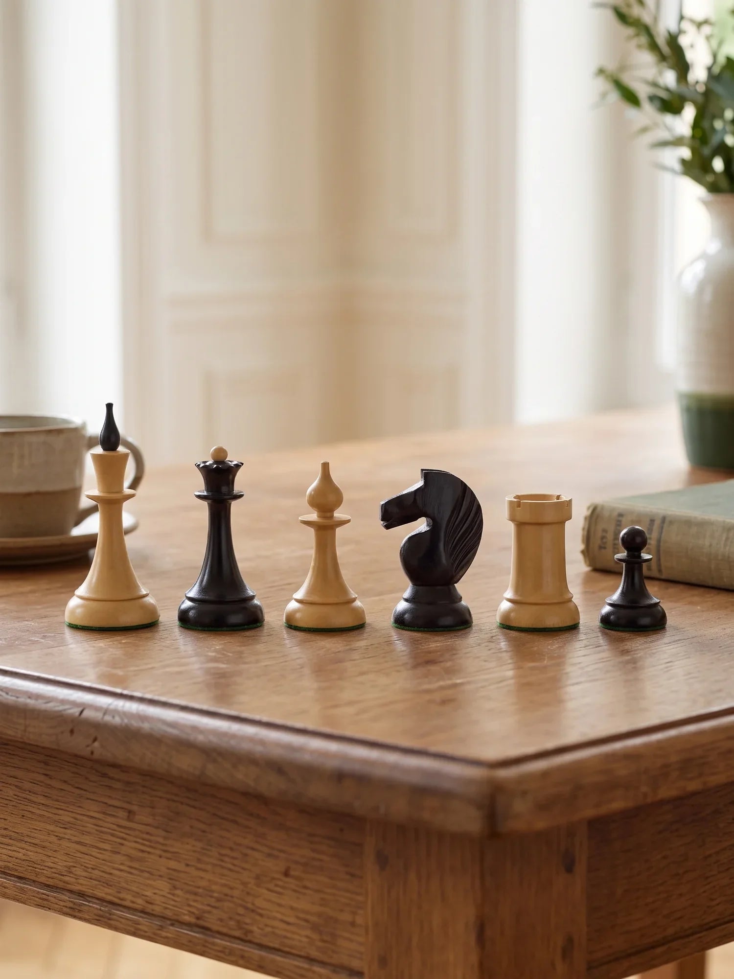 Pièces d’échecs Staunton en bois alignées sur le coin d’une table : roi, dame, fou, cavalier, tour et pion