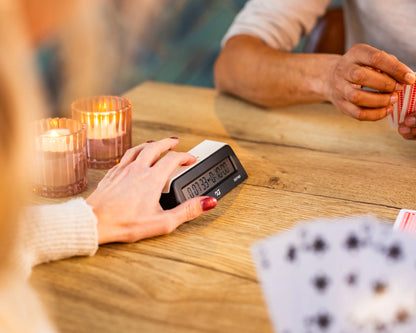 Une main appuie sur la pendule DGT 1001 posée sur une table en bois